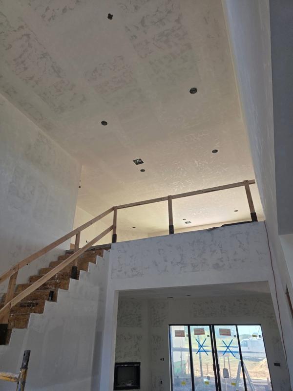 Vaulted living room with open staircase, drywall finished